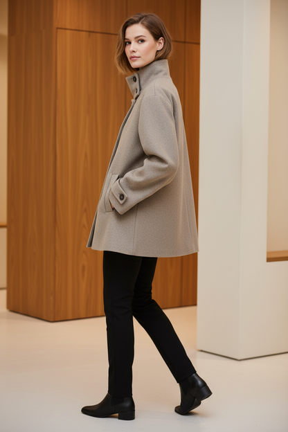 Swiss woman model showing the beige high-collar short winter coat in a boutique