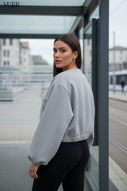 Swiss woman model showing the gray fleece cropped bomber jacket at a Zurich tram stop