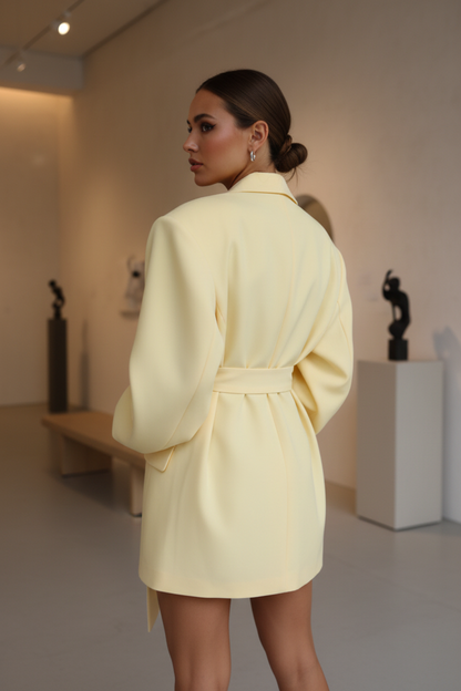 Native Swiss woman showing the solid yellow oversized belted blazer in a Swiss design gallery