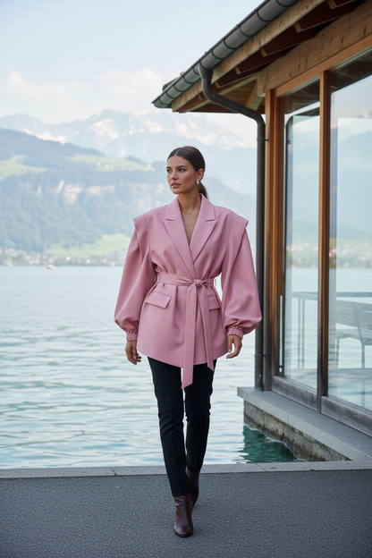 Native Swiss woman wearing the pink oversized belted blazer by a Swiss lakeside pavilion